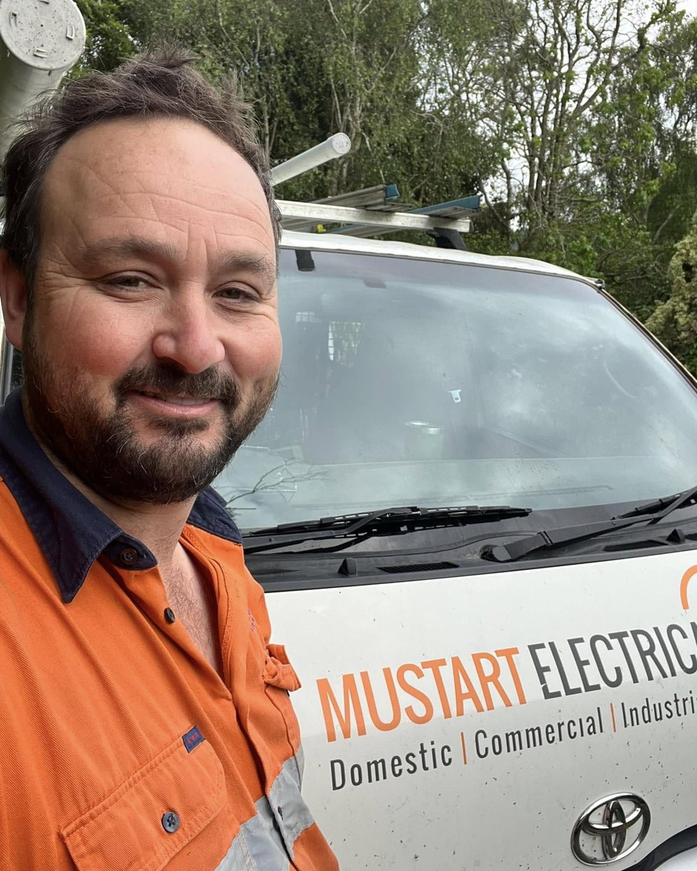 Michael Mustart beside a signwritten Mustart Electrical van
